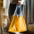 Person holding a yellow reusable shopping bag with a blurred background